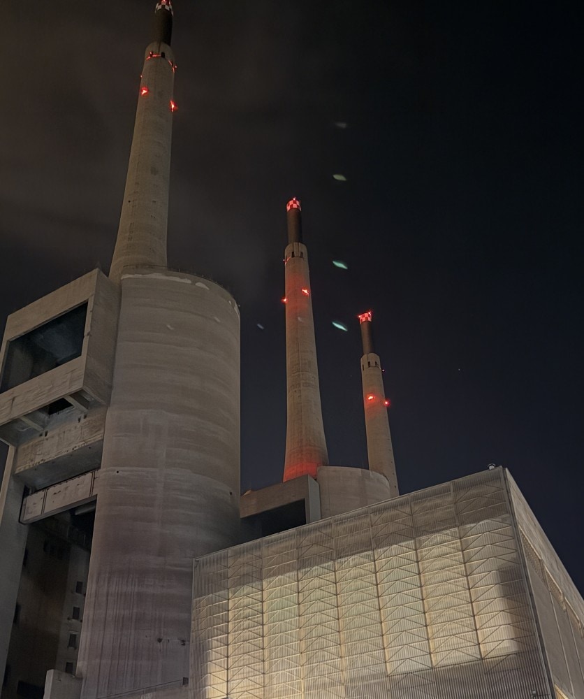 Barcelona’s Three Chimneys power plant illuminated in red at night.