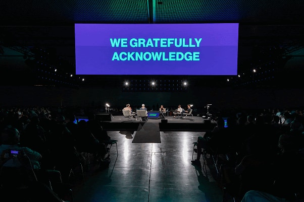 UIA 2026 plenary stage displaying the words ‘We gratefully acknowledge’ before a seated audience.