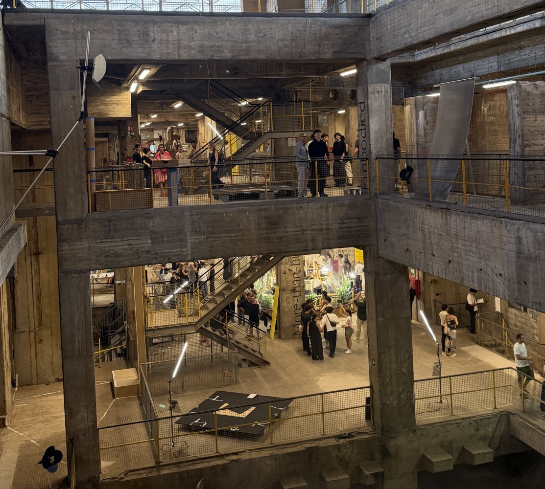 Visitors moving through the concrete interior of the Three Chimneys turbine hall.